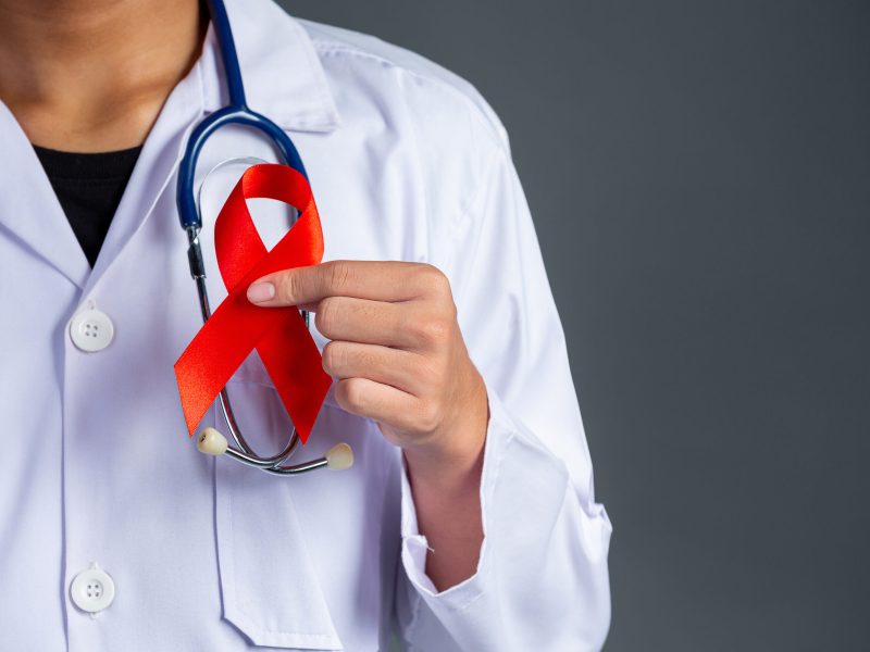 The doctor holds a red ribbon, HIV awareness awareness, World AIDS Day and World Sexual Health Day.